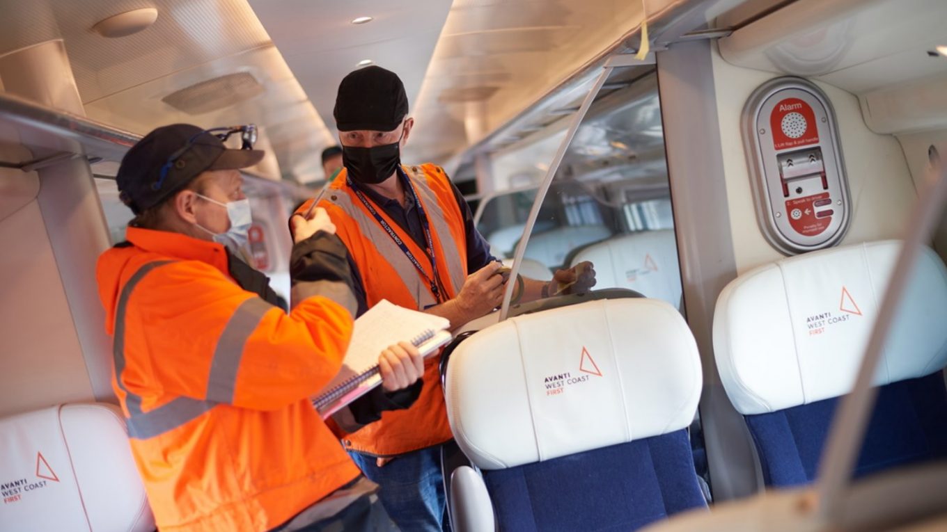 Two railway engineers in yellow hi-viz jackets inspect a newly refurbished Avanti Pendolino train.