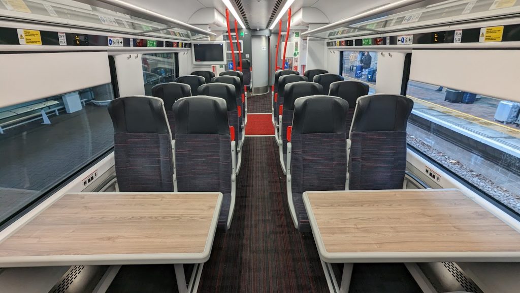 The interior of Transport for Wales 197008. There are a mixture of airline-style and table seats, and the accessible toilet can be seen in the distance.