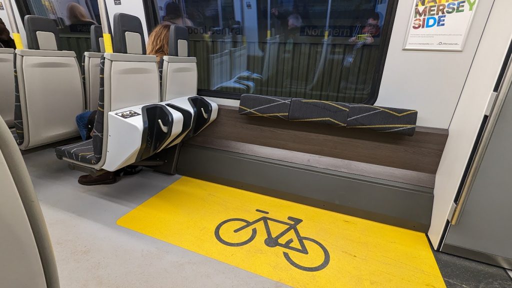 The bicycle space on a class 777 train, indicated by a yellow box on the floor and a black bicycle symbol. Next to the bike stands, there are also three perch seats.