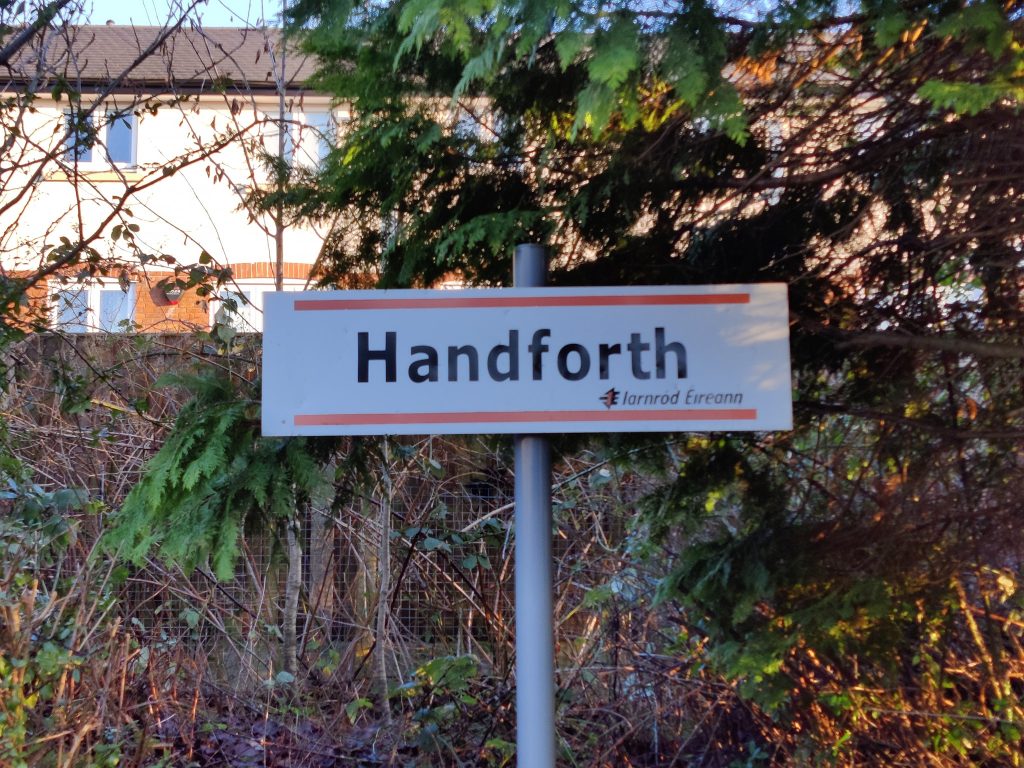 A station sign reading "Handforth" in the style of Iarnrod Eireann, the Irish national railway operator.