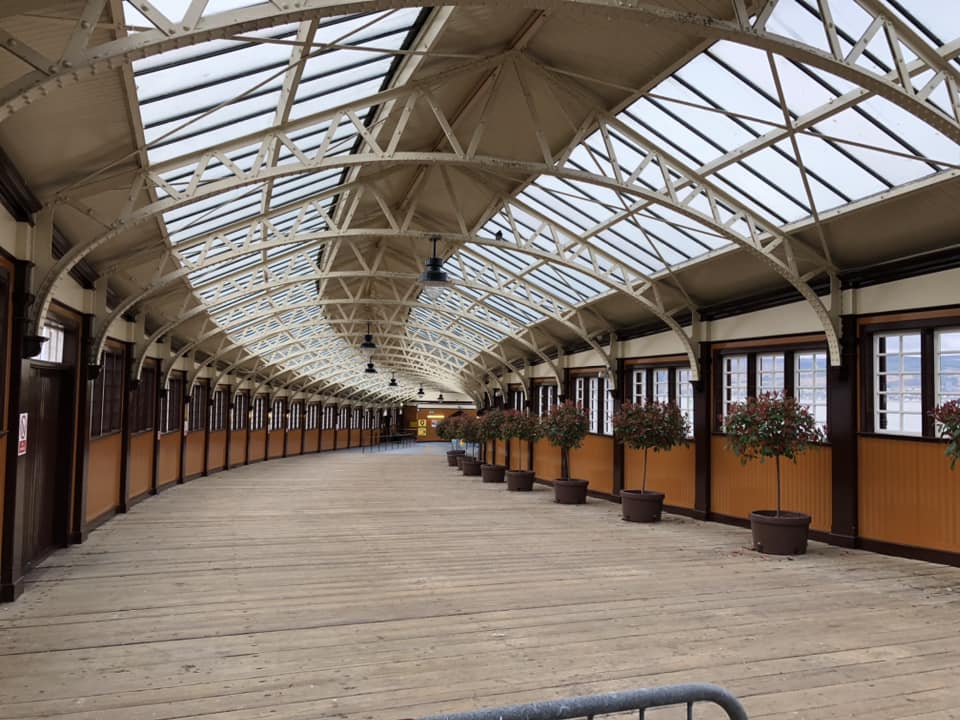 A view of Wemyss Bay station, with a glass roof. There are small trees in pots lining the right-hand wall.